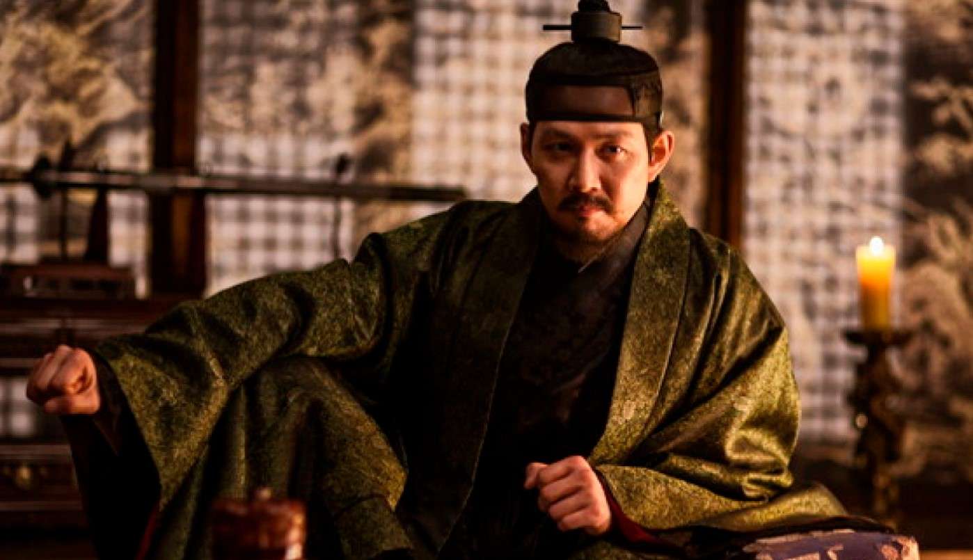Lee Jung-jae in a traditional historical robe, sitting confidently in a dimly lit room, featured in his Lee Jung-jae profile and biography.