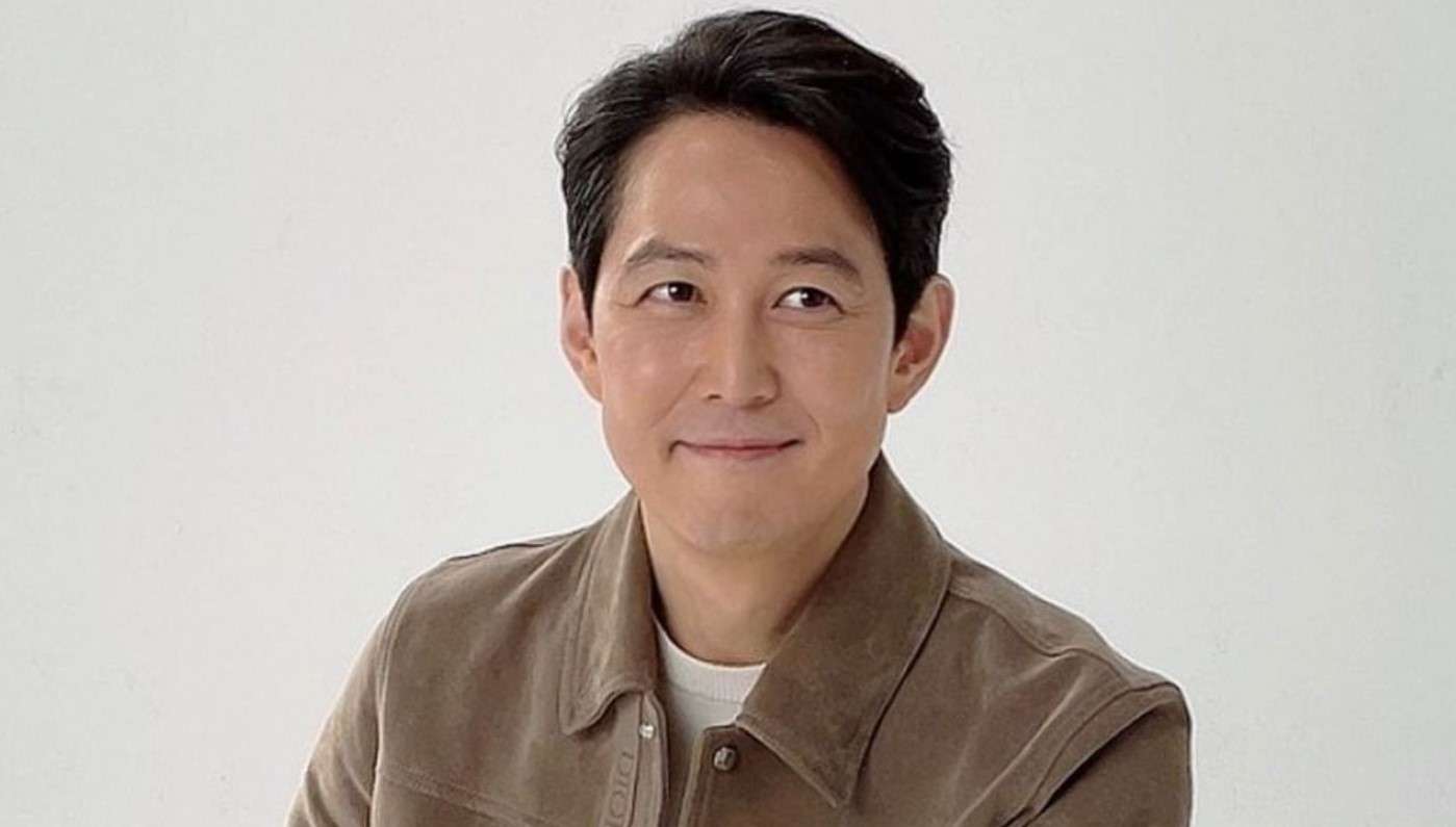 Lee Jung-jae in a stylish brown jacket and white shirt, smiling softly
