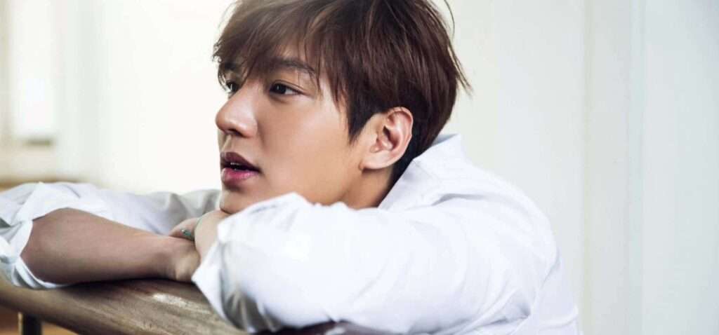 Lee Min-ho leaning on a table in a casual white shirt, showcasing a relaxed and charming side, part of his Lee Min-ho profile and biography journey in Korean dramas.