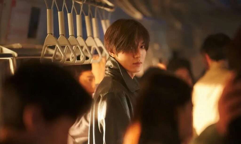 Lee Min Ho in a black jacket stands on a train, looking confidently into the distance.