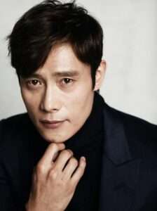 Lee Byung-hun in a black suit and shirt, showcasing his professional appearance and biography.