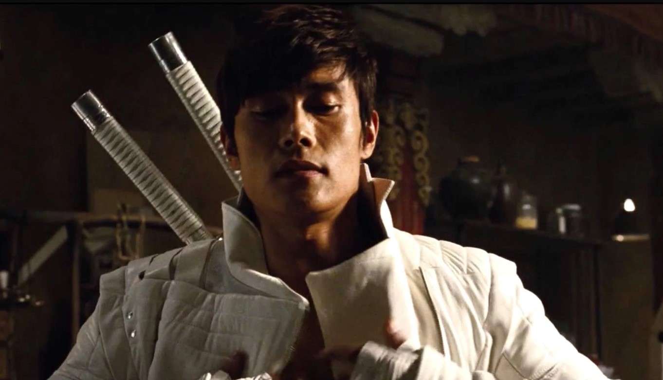 Lee Byung-hun in white attire, confidently holding two swords, showcasing his dynamic persona and martial arts skills, reflecting his Lee Byung-hun profile and biography in action.