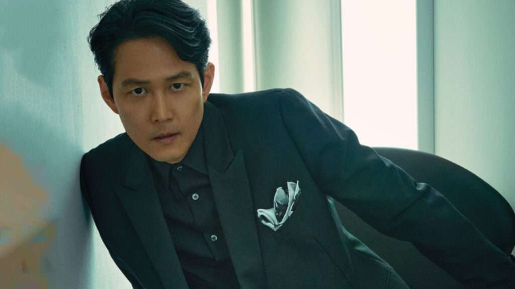 Lee Jung-jae in a stylish suit, leaning against a wall, showcasing a sophisticated look from his Lee Jung-jae profile and biography