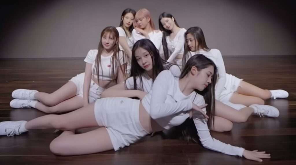 BABYMONSTER K-pop group members posing dynamically on a wooden floor in stylish white outfits, showcasing the vibrant energy of Hallyu culture in 2025