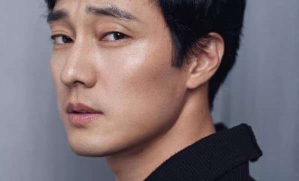 So Ji Sub in a close-up portrait with a contemplative expression, wearing a black outfit, featured in his profile and biography.